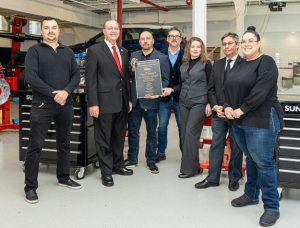 automotive tech training team poses with plaque in Patterson Garage