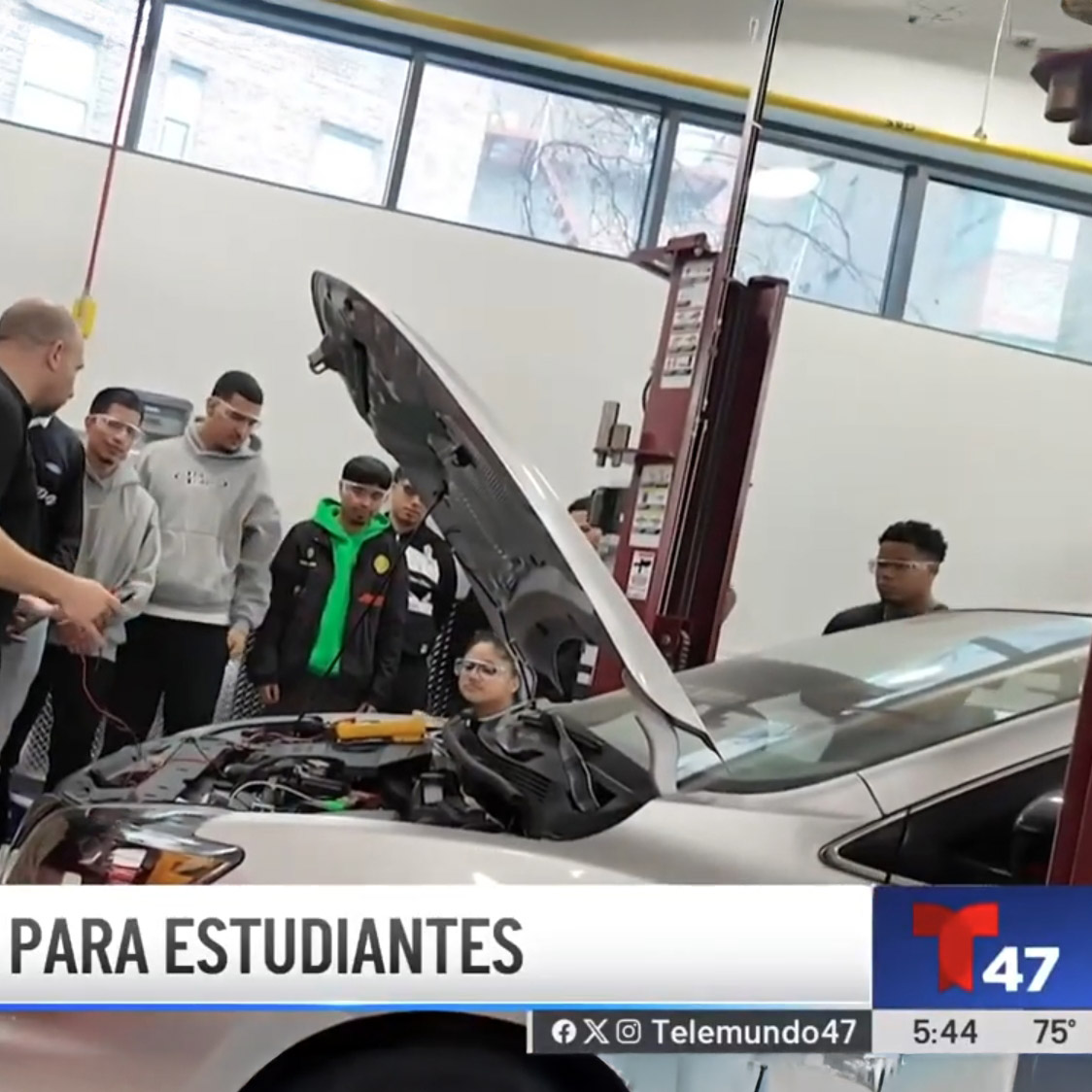 <i class="material-icons" ">article</i> Telemundo Reports on the Bronx Community College Automotive Technology Program. Instructor and students stand in front of a vehicle with its hood up.