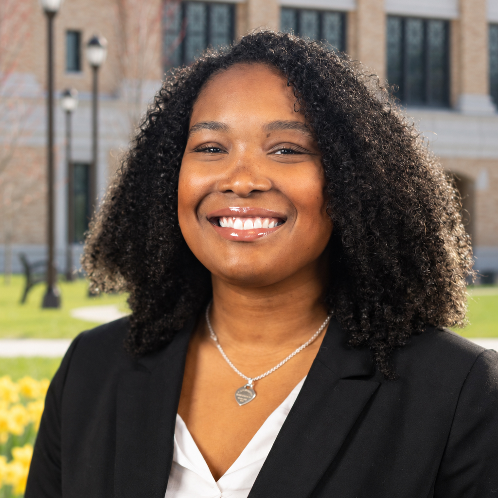 Maya Mapp smiles outdoors on the Bronx Community College campus, wearing a black blazer over a white blouse.